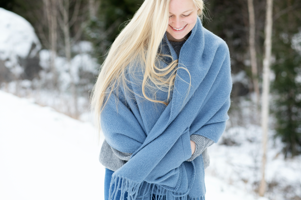 Dame med lyseblått ullsjal på vinteren.